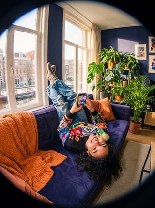 Hand houdt smartphone vast met streamingvideo in een warme woonkamer